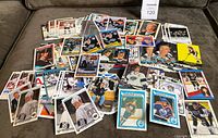 Wide view photo showing a large spread of hockey cards featuring Wayne Gretzky, laid out on a brown textured surface revealing a variety of card designs and player images.