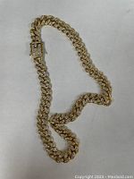 Full view of the gold tone chain link bracelet with stones and decorative clasp.