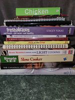 Cookbooks stacked vertically showing spines and covers with titles and authors/brands.