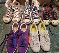 Group photo of five pairs of men's shoes showing two pairs of Converse high tops, a plaid slip-on, Puma and Adidas sneakers.
