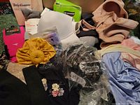 Image showing various clothing and accessory items including bras, socks, scrunchie, and shapewear in different colors and packaging.