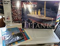 Photo of puzzle boxes including a 1000-piece Santa puzzle and a 398-piece 3D Titanic puzzle, along with the domino set contents.
