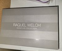 Closed black box with silver horizontal stripes labeled 'Raquel Welch Signature Collection'