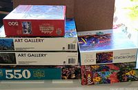 Stacked boxes of various puzzles displaying piece counts and themes.