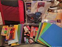 Full view of various school supplies laid out, showing binders, folders, writing instruments, glue, and small stationery items.