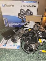 Four black cylindrical day/night security cameras with cables and installation accessories laid out with instruction manuals and connectors.
