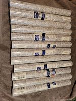 12 rolls of grey marble self-adhesive vinyl shelf liner stacked side by side on fabric surface.