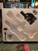 Microscope and accessories in original white foam packaging showing empty slots for remaining items.