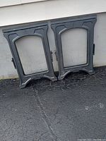 Two plastic saw horses folded and leaning against a wall, showing their rectangular frames with a top support area.