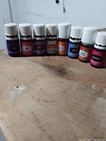 Photo showing all 8 bottles aligned, varying label colors and white caps visible, placed on wooden surface.