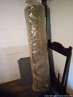 Full view of rolled carpet underpad standing upright wrapped in clear plastic.