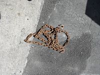 Photo showing coiled heavy-duty chain with 3/8 inch thick links and large grab hooks on both ends, resting on pavement.