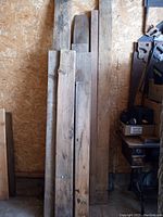 10 pieces of mixed pine lumber planks leaning against a wall showing length variation, wood grain, and knots