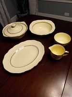 Photo of Alfred Meakin Marquis china 6-piece set on table showing platter, sugar bowl with lid, soup bowl, cream pitcher, serving dish, small bowl with marigold 18 KT gold border.