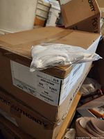 Box containing packs of white disposable face masks with a small pack of 5 masks placed on top of the box.
