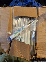 Box containing individually packaged small pocket screwdrivers with 'TRADMASTERS' branding on handles, white with blue tips.