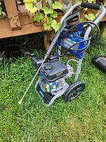 Westinghouse WPX3200 gas-powered pressure washer placed on grass outdoors, showing the machine, coiled hose, spray wand, and two large wheels on the frame.