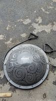 Top down view of the Atrivafit branded bouncer exerciser laid on asphalt with rubber resistance straps seen coiled beside it.