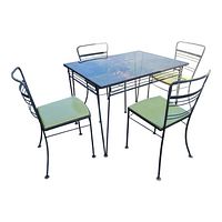 Full view of vintage iron patio table and four chairs with smoked glass top and green vinyl cushions.