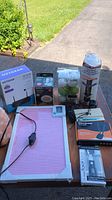 Overview of lot items including Himalayan salt lamp, peg board, coffee maker and electronic devices on table in outdoor setting.