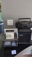 Lot of 4 electronic items including Westinghouse boombox on top of RMS speaker, Garmin GPS in box, and Sears 5-inch portable TV below