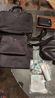 Photo showing the The Sak black nylon purse shoulder bag, Bovi black leather wallet on brown leather item, Frye brown leather pouch, Ellie cosmetic bag, and skincare products.
