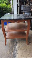 Full front view of the side/end table showing black marble top and wooden frame with two lower shelves