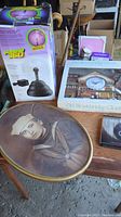 Photo showing Plasma 360 light in original box, Old Stockbridge clock box, vintage oval framed military portrait, two audio cassettes, Old Navy photos, and packing material on wooden table.