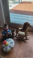 Photo showing the vintage decanter, Bakelite coffee cup, wooden rocking horse music box, and the colorful metal spinning top all together on the floor.