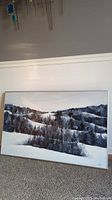 Framed oil painting of a winter forest landscape with snow-covered hills and trees.