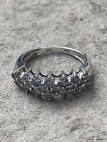 Front view of ring showing three rows of diamonds set in white gold band.