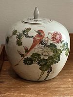 Front side of the porcelain ginger jar showing bird and flower hand-painted decoration on bulbous body.