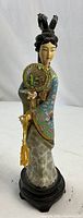 Full frontal view of the Chinese cloisonne and enamel figurine featuring the woman in traditional dress holding a round fan, standing on a wooden base.
