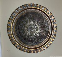 Full front view of the round brass charger showing scalloped rim and central relief scene