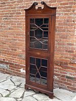 Full view of mahogany corner cabinet showing overall form, glass multi-panel doors, bracket feet, swan’s neck pediment