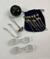Full lot showing George Jensen sterling silver ladle, tongs, two crystal utensil holders and themed appetizer skewers in blue velvet pouch with green glass apple for size reference.