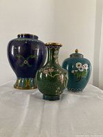 Front view of three cloisonne items displaying decorative colors and motifs