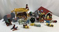 Full view of the wooden circus set featuring animals, a wagon, and a ringmaster figure, arranged with a green apple for size reference