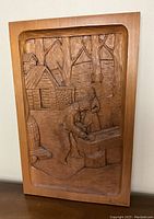 Front view of carved relief showing two figures, sugar shack and barrels
