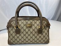 Full front view of beige GG monogram canvas bag with brown leather trim and gold-tone hardware