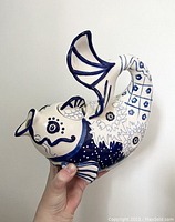 Side view of blue and white koi fish shaped stoneware tea pot showing detailed hand-painted patterns of flowers, dots, and scales on the body and tail.