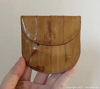 Front side of the wallet showing curved flap closure and vertical eel skin segments with natural texture and color variations.