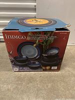 Closed box labeled Indigo 16-piece dinnerware set with photo of blue gradient plates and bowls on the packaging.