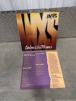 INXS Listen Like Thieves vinyl record sleeve with two lyric sheets laid out in front.