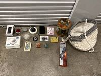 Wide view of all items in the miscellaneous lot arranged on floor showing electronics, basket, tins, and various decorative pieces.