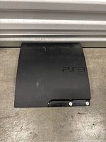 Top view of Sony PlayStation 3 console showing PS3 logo and surface scratches