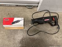 Photo showing the Craftsman reciprocating saw and the boxed Jobmate rotary tool kit placed on the floor.