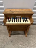 Front view of the vintage Schoenhut toy piano showing the keyboard and wooden body with wear.
