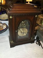 Front view of the wooden mantle clock showing clock face and casing details.