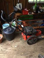 Side view of orange deck mower with black engine and push handle